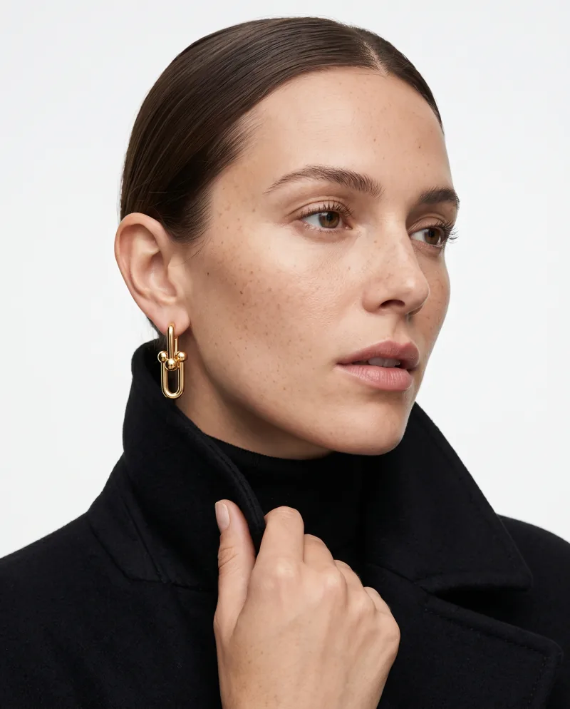 The gold link earring worn with a black coat, generated
