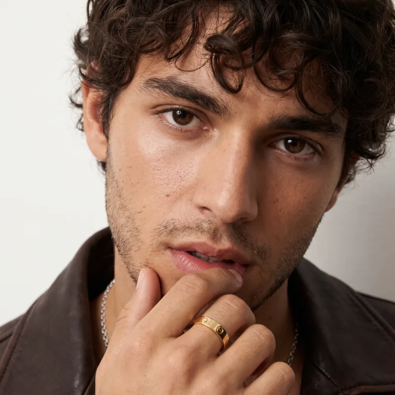 The ring worn by a male cast model, hand at the mouth — a social post