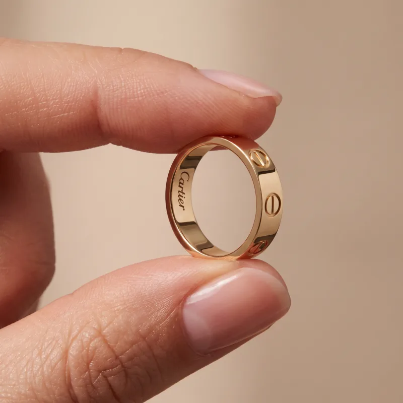 The ring held between two fingers — a campaign creative